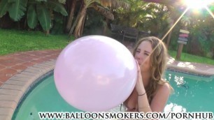 Busty teen blows to pop balloons outside in pool